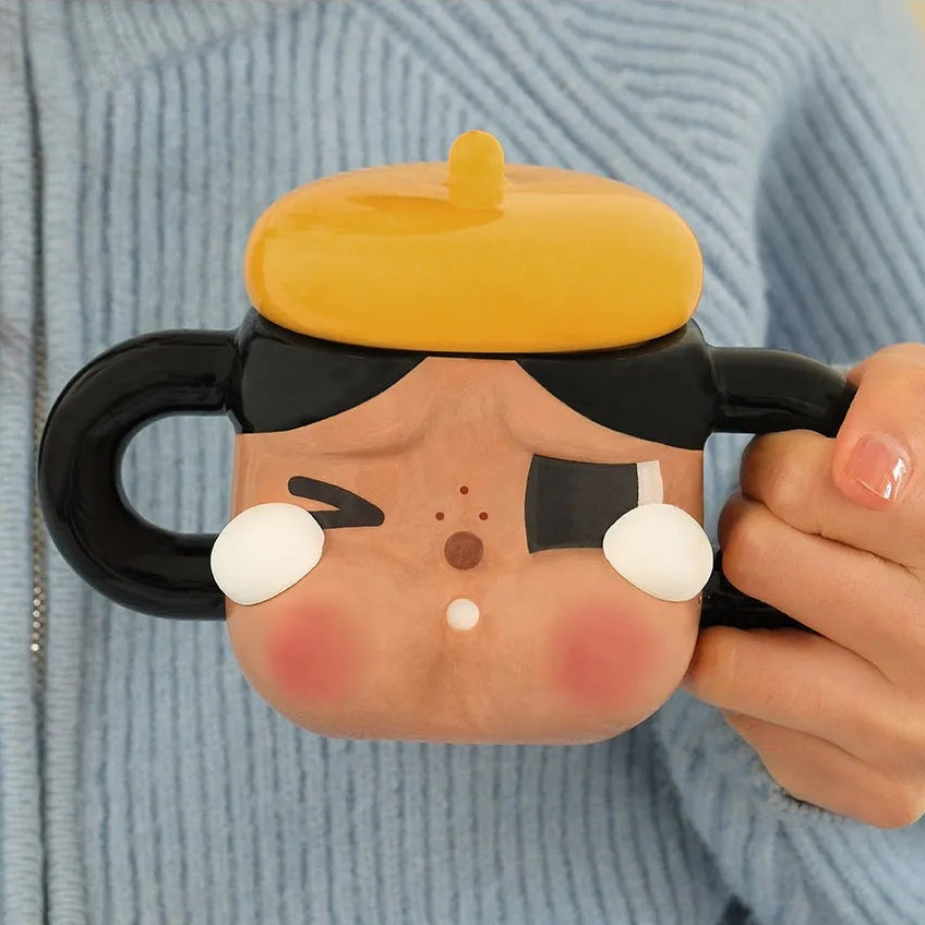 Person holding a cartoon character mug with a blue sweater background
