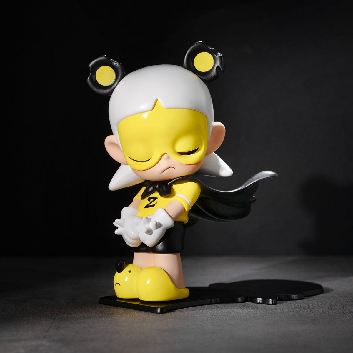 Animated character figurine with yellow face and black hair on a dark background