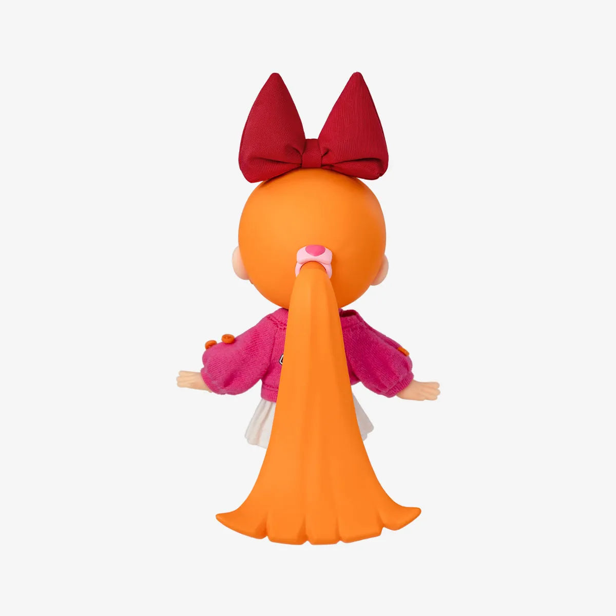 A stylized doll or figurine shown from the back on a plain light gray background. The figure has a round orange head, a long orange ponytail with a pink bow, a large dark red bow on top, and a pink outfit with white accents.