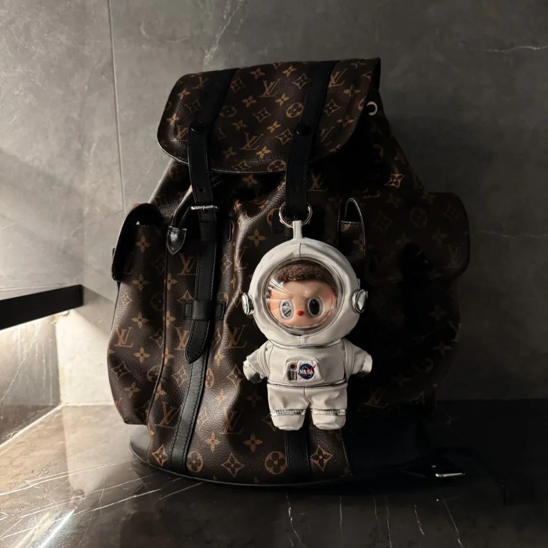 Designer backpack with LABUBU astronaut suits keychain on a marble floor