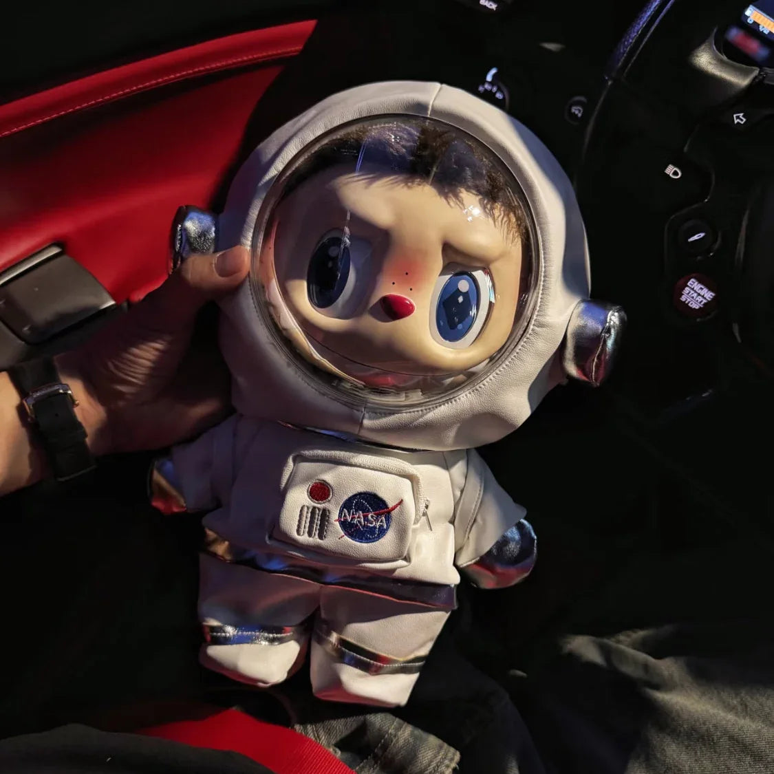 labubu in an astronaut suit with a NASA logo inside a vehicle.