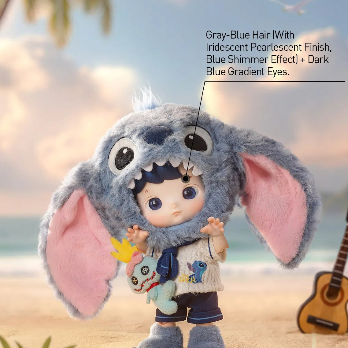 A product showcase image of a collectible doll dressed in a large gray-blue Stitch-like character costume with pink inner ears, standing on a sandy beach with a beach umbrella, palm leaves, and a ukulele in the background. Text on the image describes the doll's gray-blue hair and blue gradient eyes.