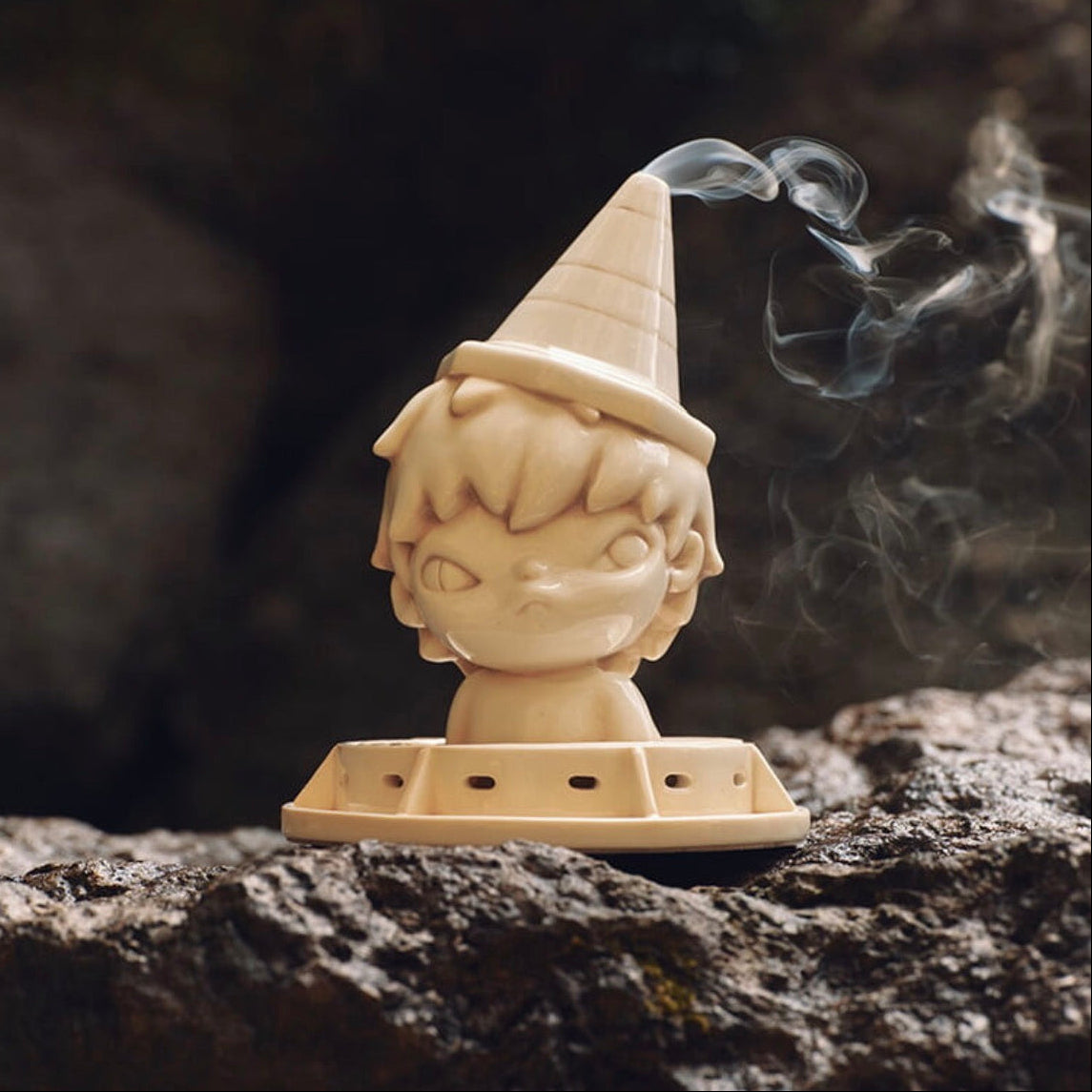 Gnome-shaped incense burner with smoke on a dark stone surface
