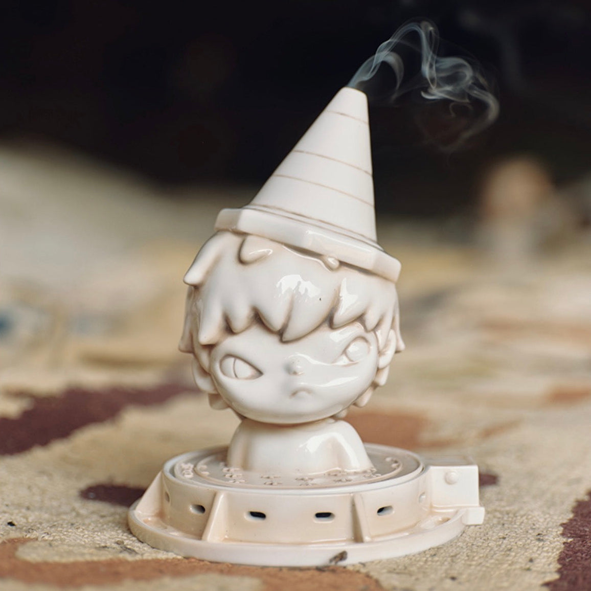 Gnome-shaped incense burner with smoke on a textured surface