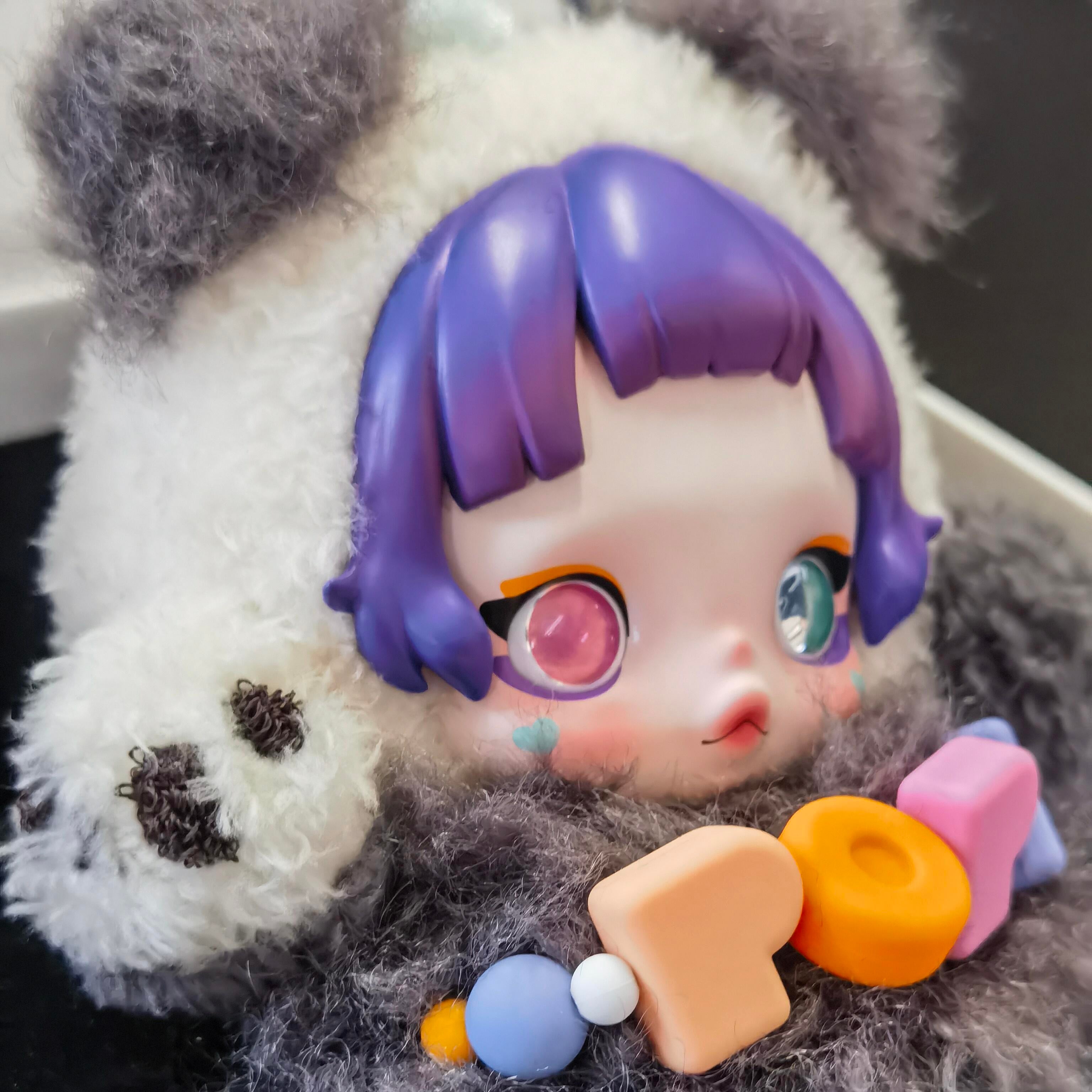 Toy figure with purple hair and colorful accessories on a panda-like body