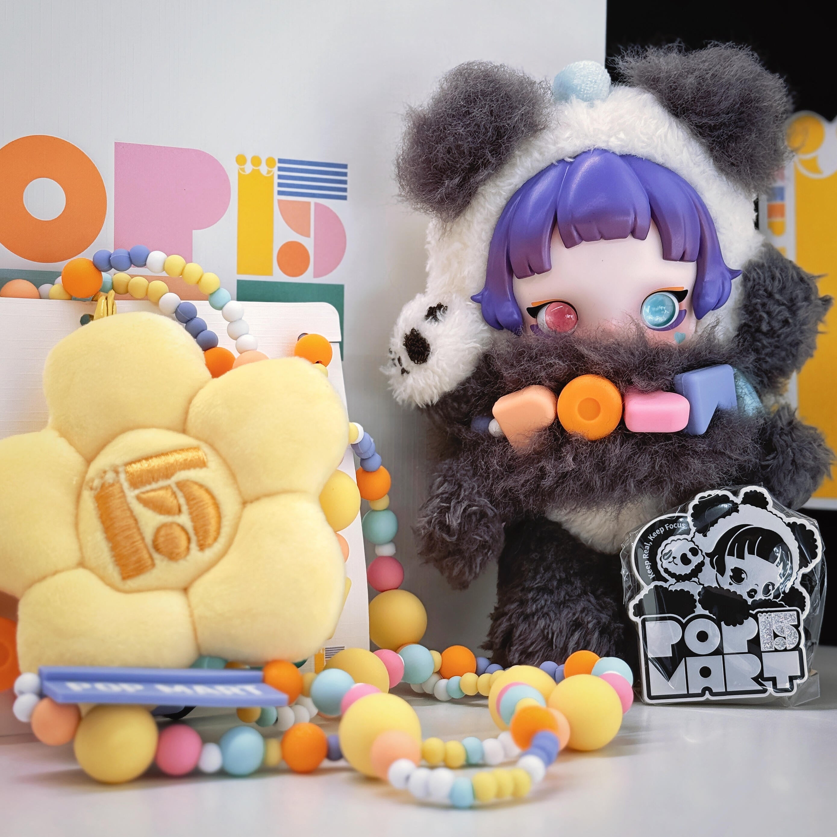 Plush toy with panda ears and colorful accessories next to a colorful 'POPS' sign.