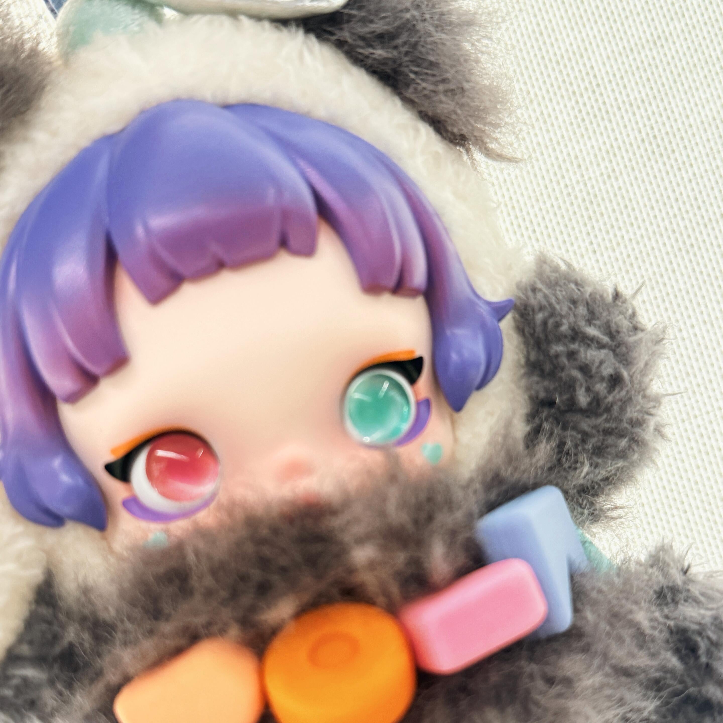 Toy figure with purple hair and colorful accessories on a neutral background