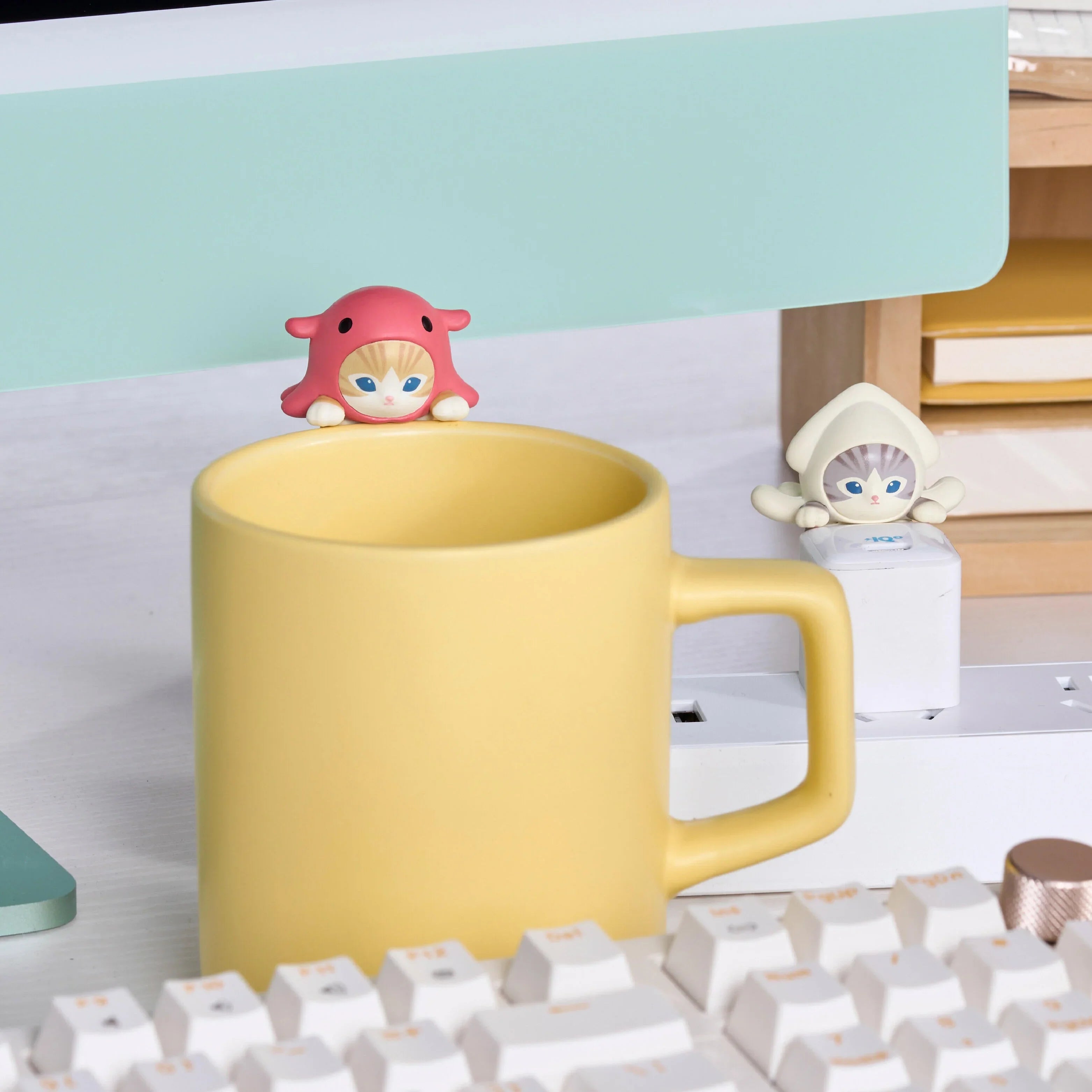 Yellow mug with decorative mini figure on a desk, featuring mofusand branding.