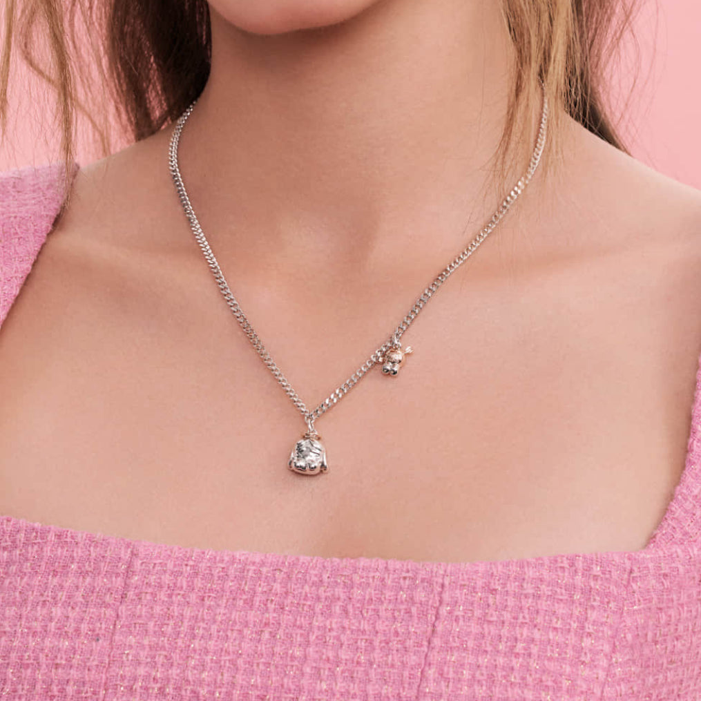 Necklace with a pendant worn by a person in a pink top against a pink background