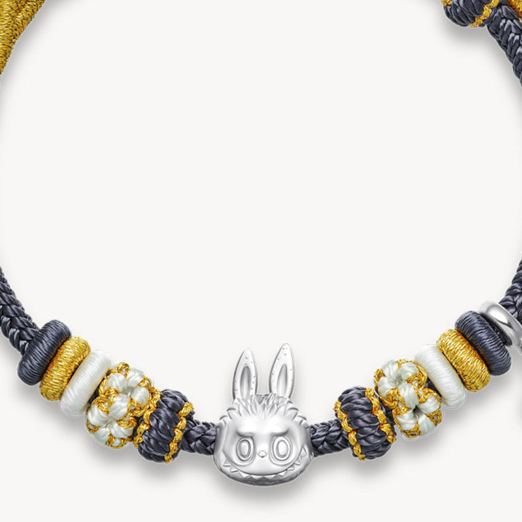 Bracelet with braided design, beads, and a silver bunny charm on a white background