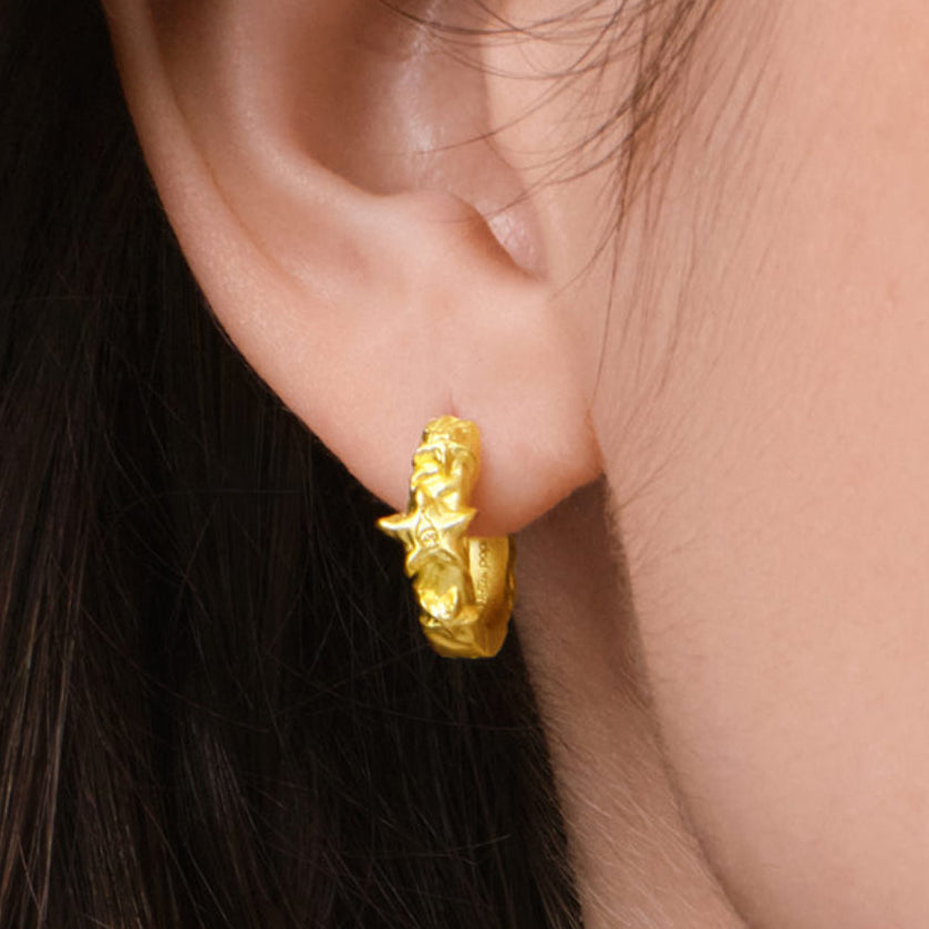Gold hoop earring worn by a person with dark hair.