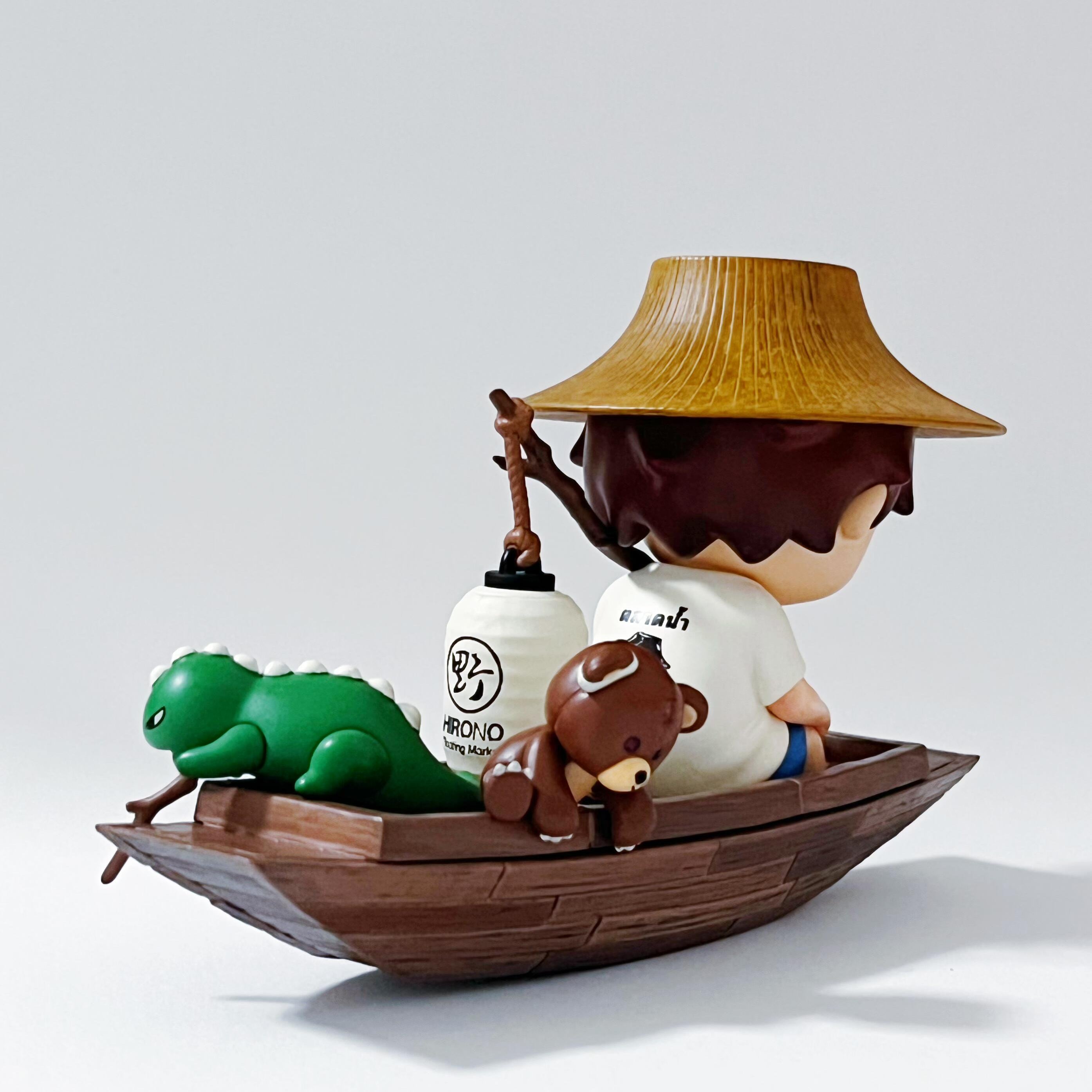 Figurine of a person with a hat on a boat with a green creature, on a light gray background