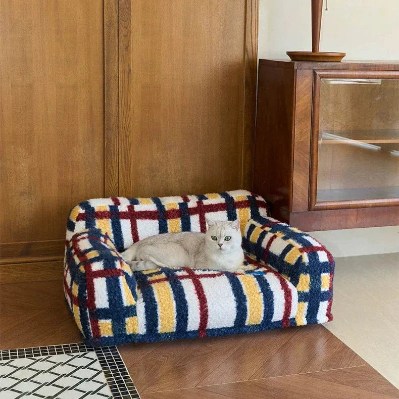 Colorful patterned pet bed with a cat inside in a room with wooden walls and a lamp.