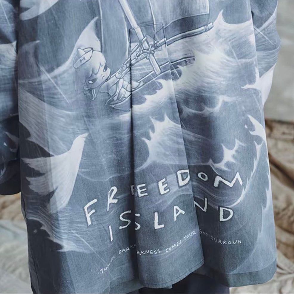 A draped gray and white printed fabric, likely a scarf or shawl, featuring the text 'FREEDOM IS LAND' and a graphic of a vintage airplane over waves. The top panel shows it styled on beige bedding, and the bottom panel shows a close-up of the printed pattern.