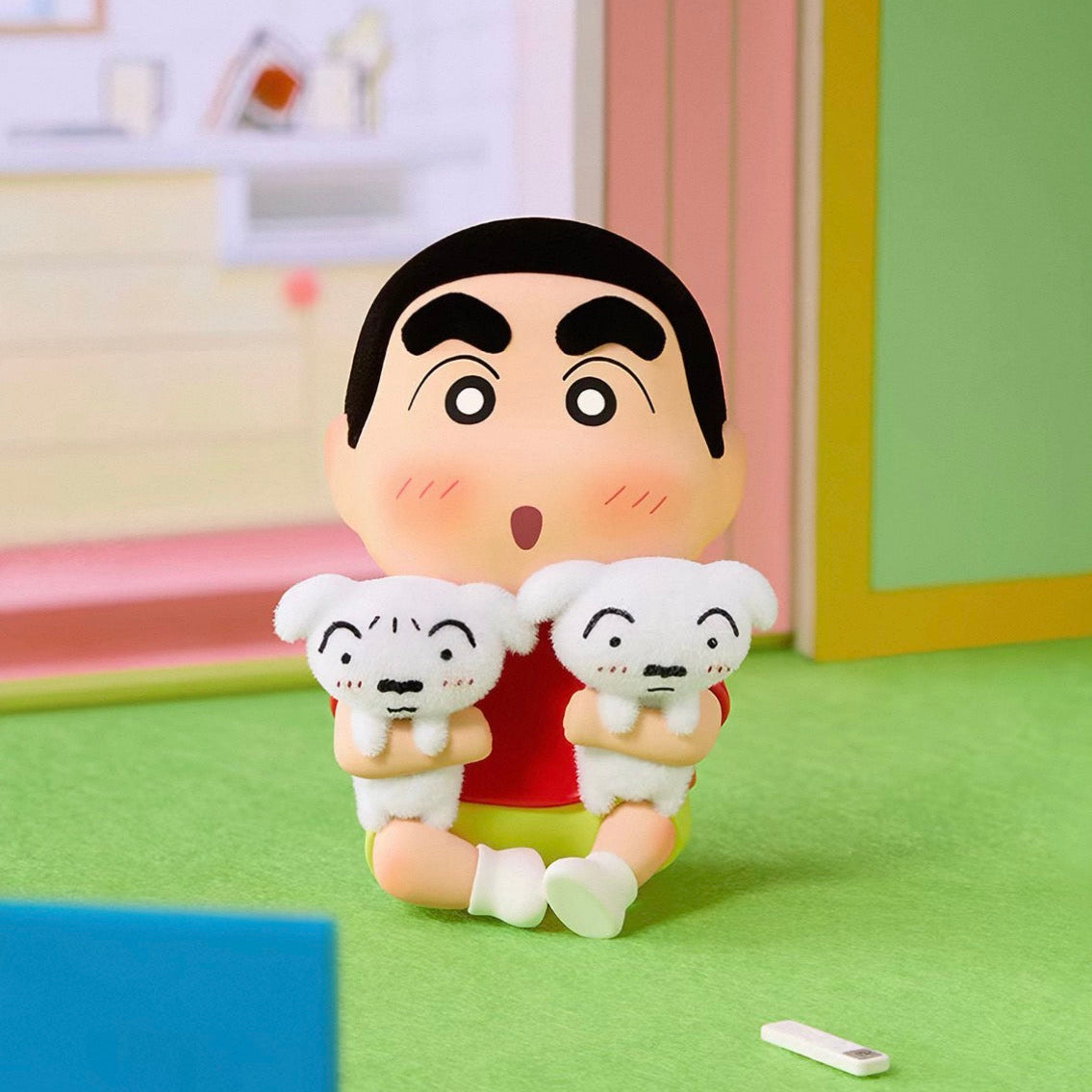 A Shin-chan collectible figurine holding two white puppies, set against a miniature pastel-colored room backdrop.