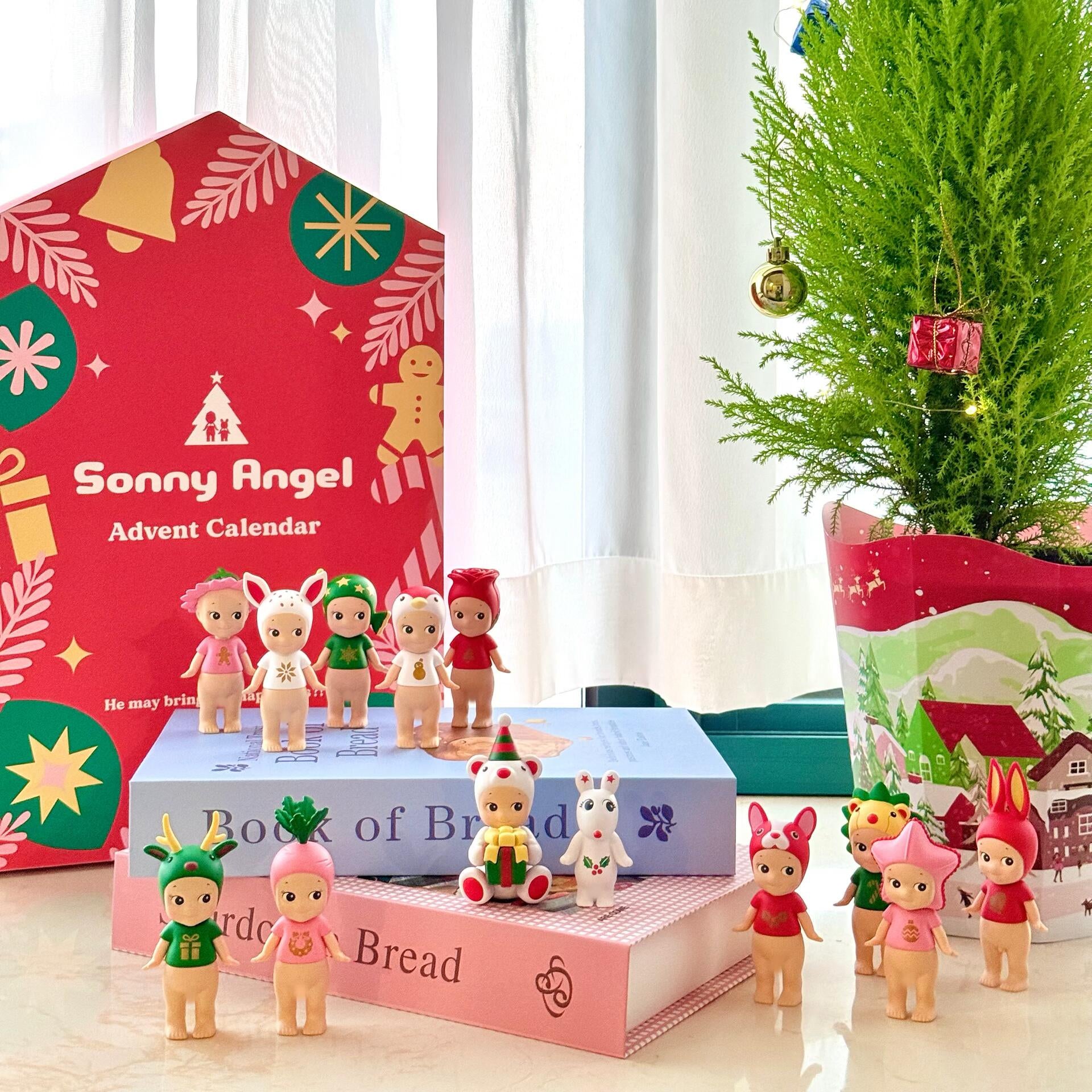 Sonny Angel Advent Calendar with small figurines on a table next to a Christmas tree.