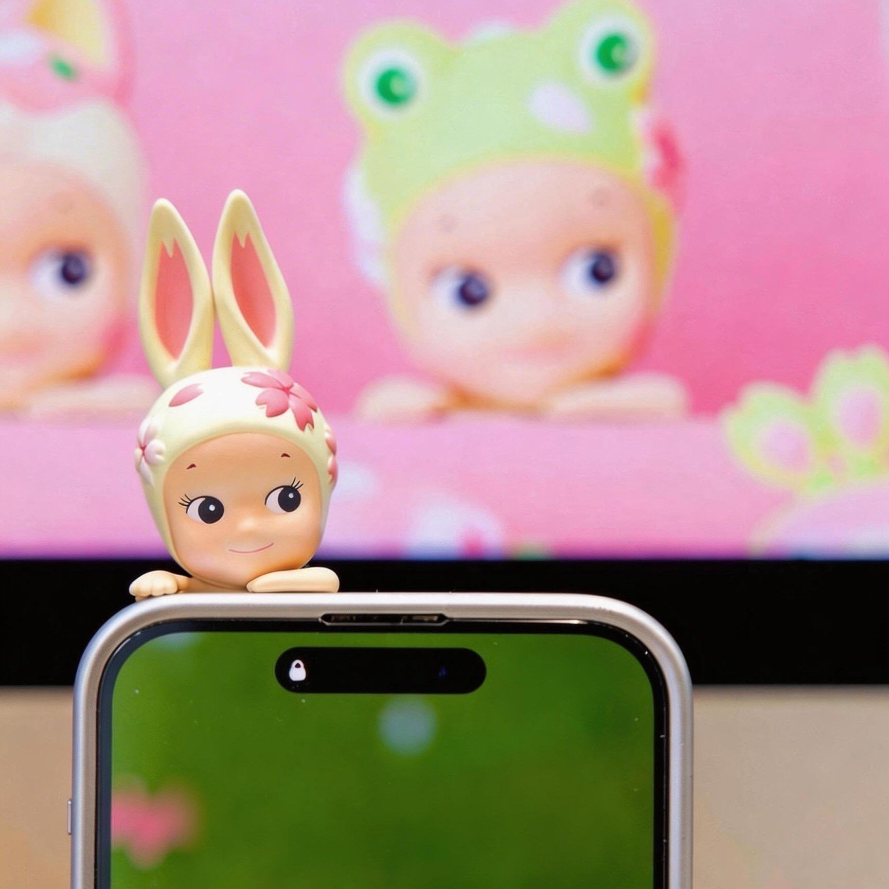 Phone with a small figurine on top, set against a colorful background with rabbit hippers