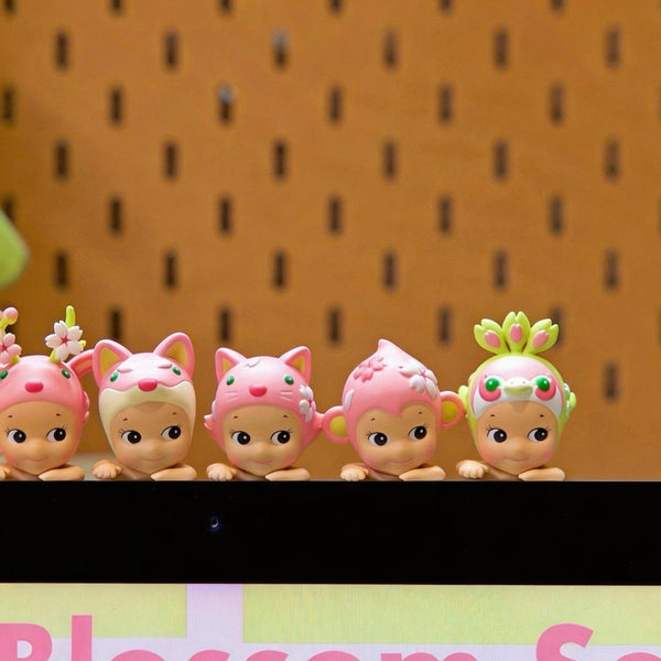 Five cartoon-style figurines with a 'Blossom Ser' text overlay on a green background.