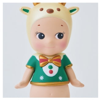 A split-view product photo showing a stylized doll or figurine from the chest up. The left panel shows the full figure wearing a green holiday outfit with a bow tie and a cream reindeer-style headpiece with green ears.