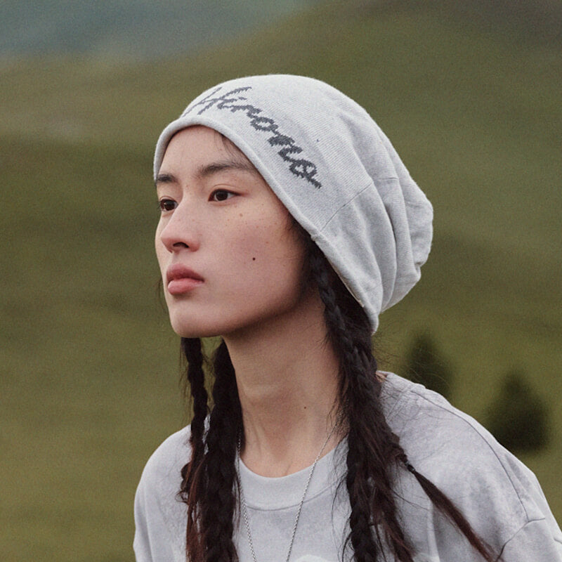 Model wearing POP MART HIRONO Whisper Within cement gray beanie with logo