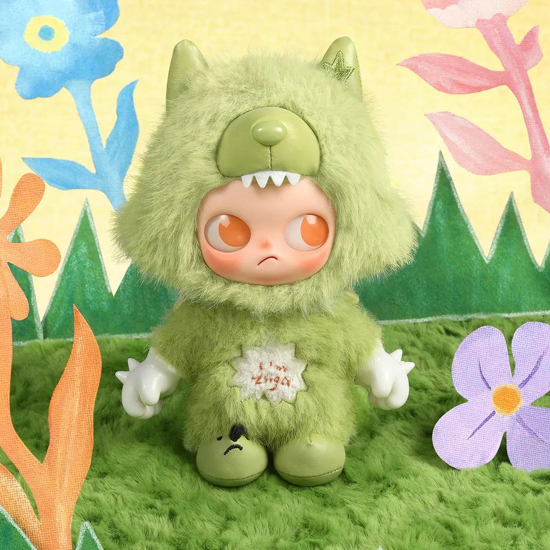 Green plush toy with orange eyes in a colorful, cartoon-like landscape with flowers and trees.