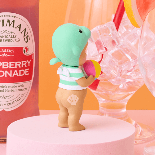 Fentimans Raspberry Lemonade bottle with a small figurine of a turtle in a swimsuit on a pink surface.