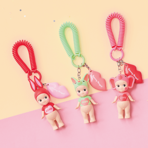 Set of colorful keychains with cartoon character figures on a pink and yellow background