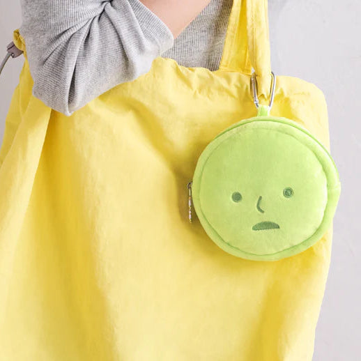 Yellow tote bag with a green round pouch featuring a sad face on a gray background