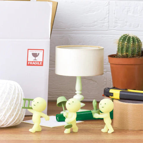 Small green figures on a desk with office supplies and a cactus plant.