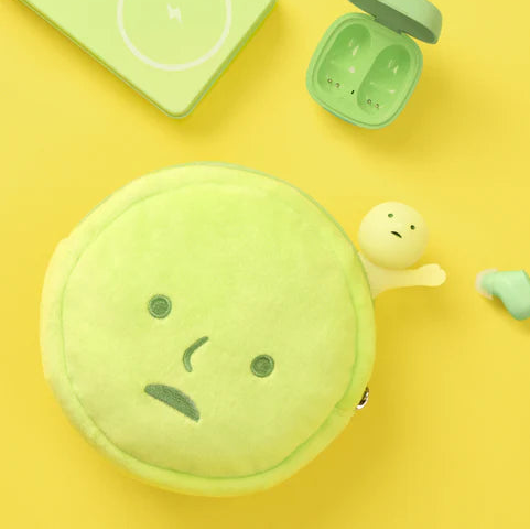 Green cushion pouch with a face design on a yellow background, featuring the brand 'Smiski'.