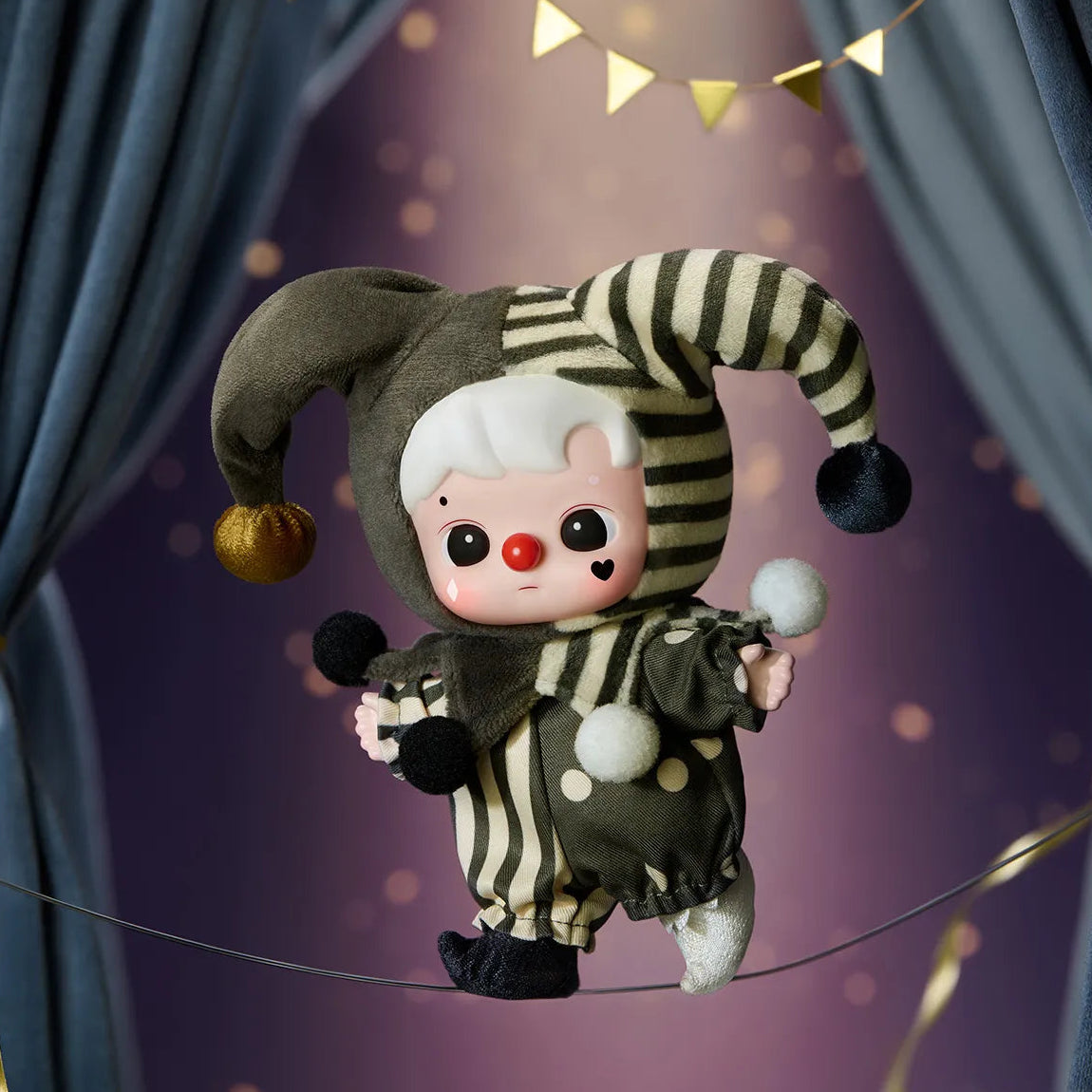 Clown figurine with striped hat and red nose on a stage with curtains and lights.