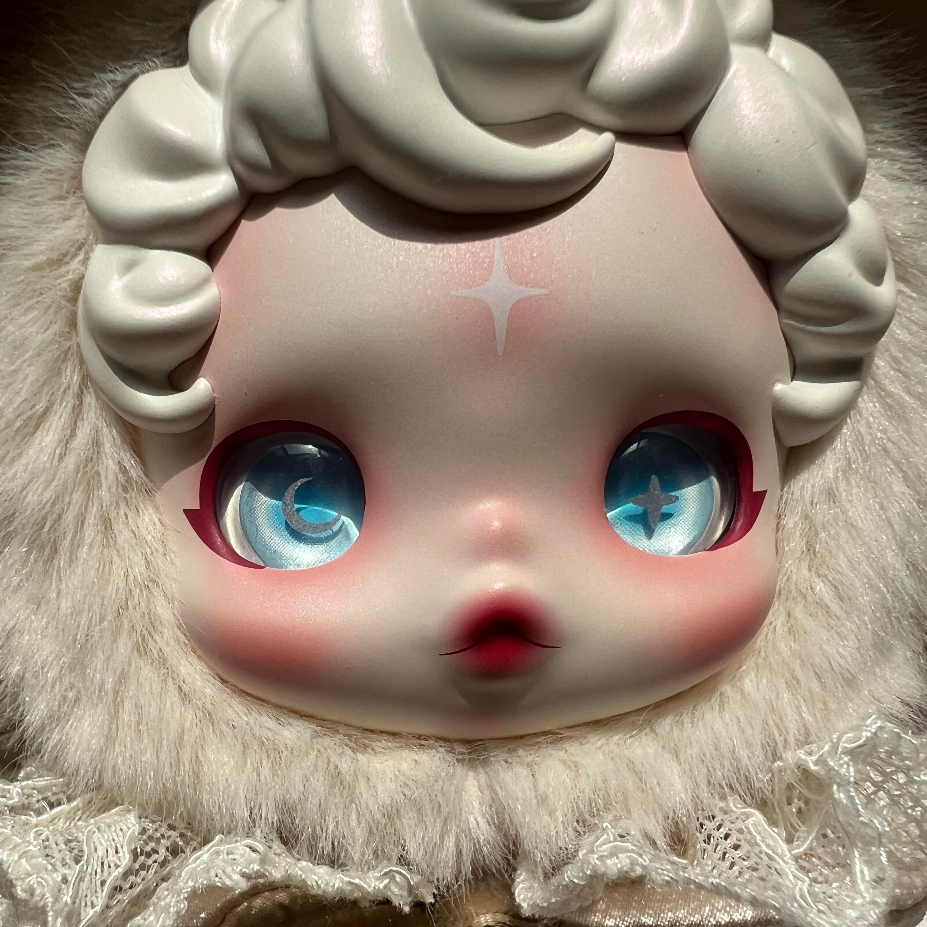 Close-up of a doll with large blue eyes and white hair, wearing a lace outfit.