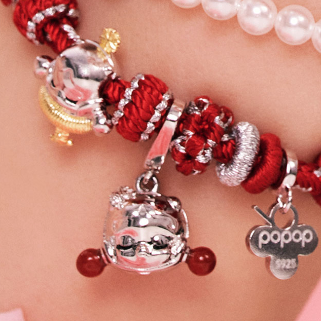 Bracelet with red and silver charms on a person's wrist