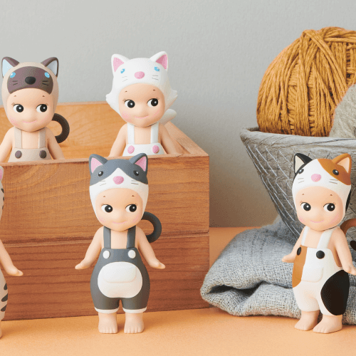 Set of small figurines with animal-themed outfits on a wooden surface with yarn balls in the background.